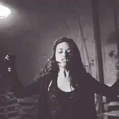 A Woman In A Black And White Photo Is Dancing In A Dark Room . GIF