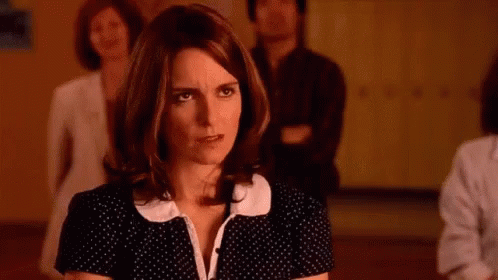 A Woman In A Black And White Polka Dot Dress Is Standing In A Room With Other People . GIF