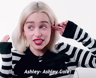 A Woman In A Black And White Striped Sweater Is Covering Her Ears With Her Hand . GIF