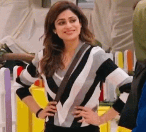 a woman in a black and white striped sweater is standing with her hands on her hips .