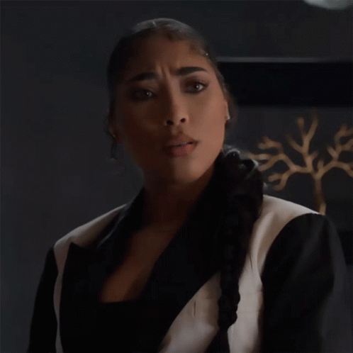 A Woman In A Black And White Suit Is Making An Okay Gesture GIF