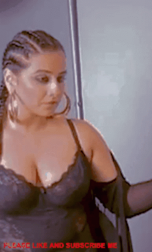 A Woman In A Black Bra And Hoop Earrings Is Standing In Front Of A Door . GIF
