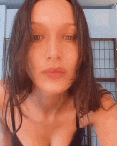 A Woman In A Black Bra Is Taking A Selfie In Front Of A Window . GIF