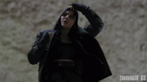 A Woman In A Black Coat Is Holding Her Hair In A Ponytail .. GIF