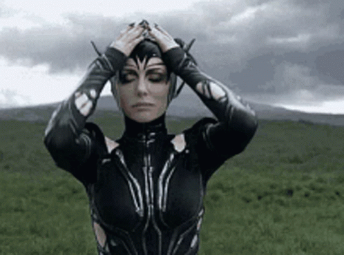 A Woman In A Black Costume Is Standing In A Field With Her Eyes Closed . GIF