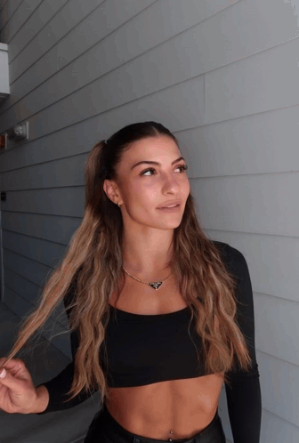 a woman in a black crop top is standing in front of a building