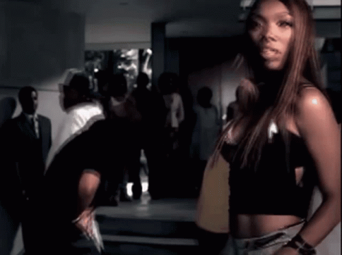 Woman In Black Crop Top Standing Next To Man In Black GIF