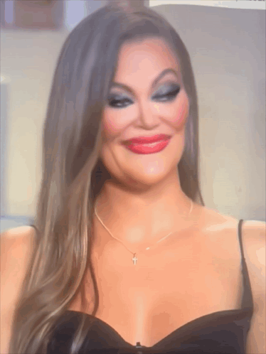 A Woman In A Black Dress Has A Cross Necklace GIF