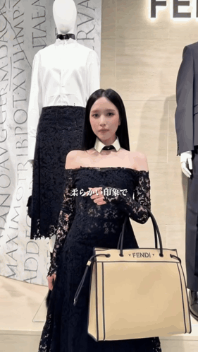 a woman in a black dress holding a fendi bag