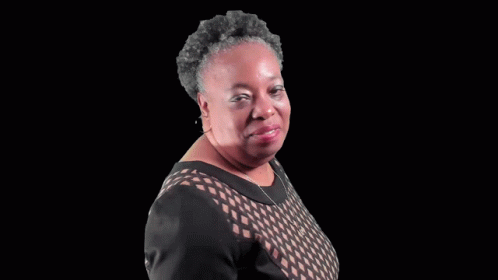 A Woman In A Black Dress Is Blowing A Kiss To The Camera . GIF