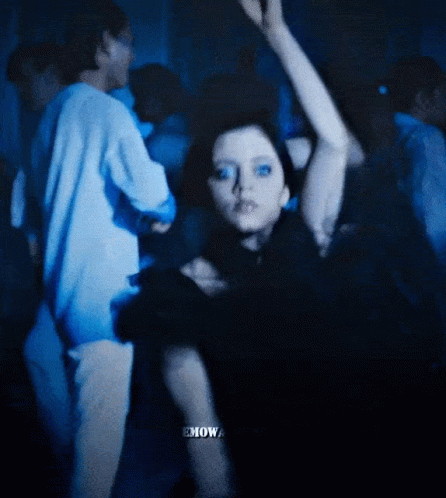 A Woman In A Black Dress Is Dancing In A Crowd With The Word Emow Visible GIF