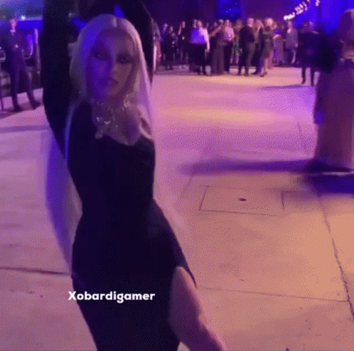 A Woman In A Black Dress Is Dancing In Front Of A Crowd And The Caption Says Xobardigmer GIF