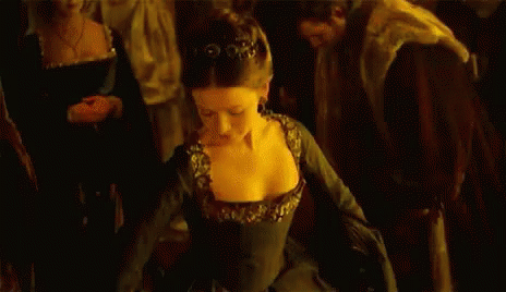 A Woman In A Black Dress Is Dancing In Front Of A Crowd Of People In A Dark Room . GIF