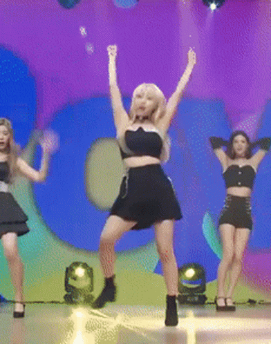 A Woman In A Black Dress Is Dancing On A Stage In Front Of A Large Number 5 GIF