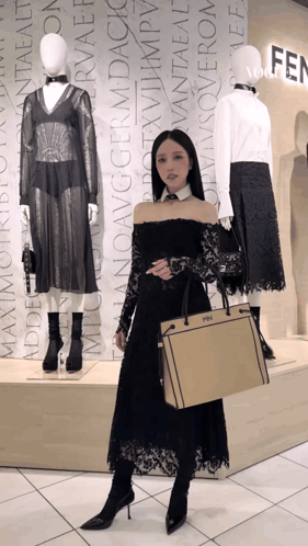 a woman in a black dress is holding a fendi bag in front of mannequins
