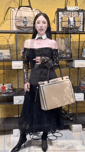 a woman in a black dress is holding a fendi purse