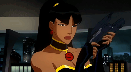 A Woman In A Black Dress Is Holding A Gun With The Letter S On Her Chest GIF