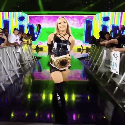A Woman In A Black Dress Is Holding A Wrestling Championship GIF
