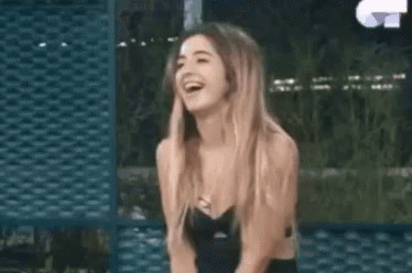 A Woman In A Black Dress Is Laughing While Sitting Down . GIF
