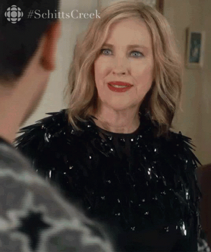 A Woman In A Black Dress Is Looking At A Man In A Room . GIF
