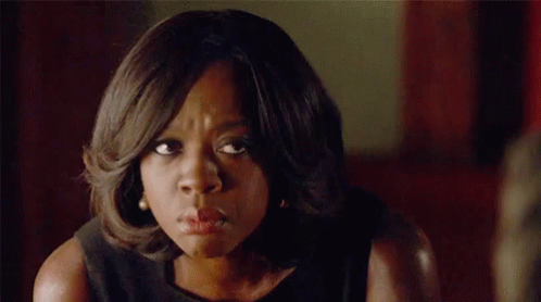 A Woman In A Black Dress Is Making A Funny Face And Looking At The Camera . GIF