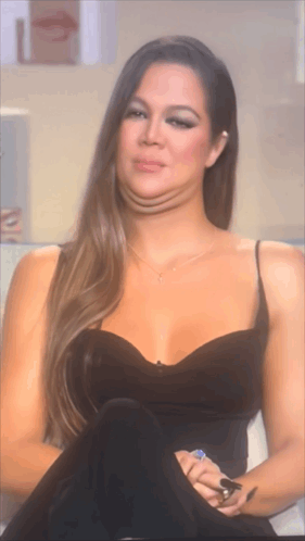 A Woman In A Black Dress Is Making A Funny Face With Her Mouth Open GIF