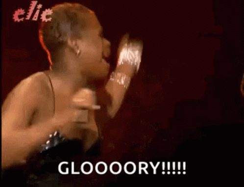 A Woman In A Black Dress Is Singing Into A Microphone And Says Gloooory . GIF