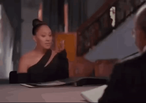 a woman in a black dress is sitting at a table with a man .