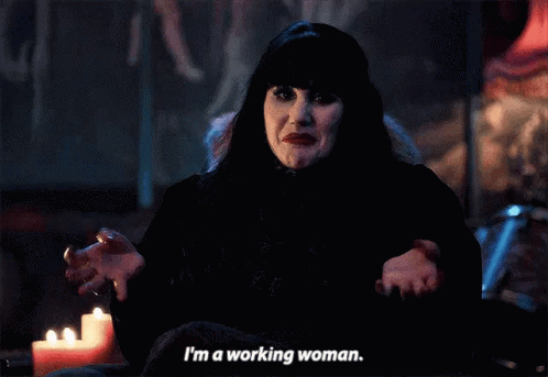 A Woman In A Black Dress Is Sitting In Front Of A Candle And Says I 'M A Working Woman . GIF