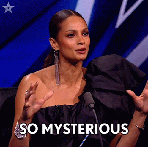A Woman In A Black Dress Is Sitting In Front Of A Microphone And Says " So Mysterious " GIF