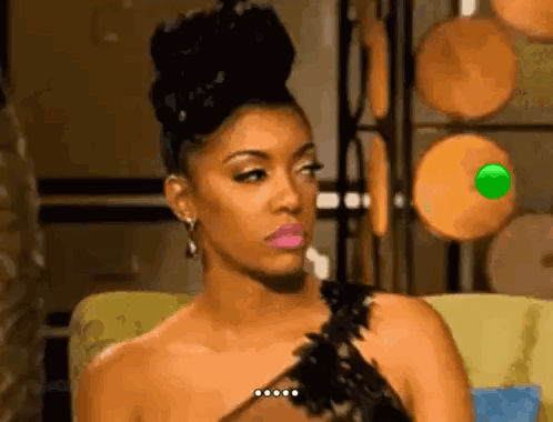 A Woman In A Black Dress Is Sitting On A Couch With A Green Object In Her Eye . GIF