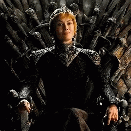A Woman In A Black Dress Is Sitting On A Wooden Throne . GIF
