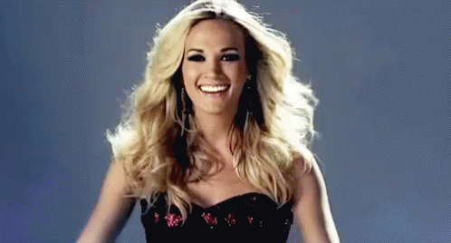 A Woman In A Black Dress Is Smiling And Dancing . GIF