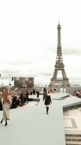 A Woman In A Black Dress Is Smiling And Walking . GIF