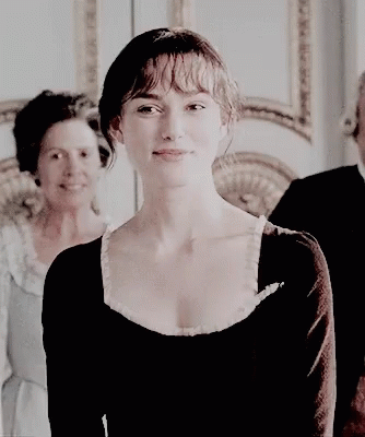 A Woman In A Black Dress Is Smiling While Standing Next To A Man And Woman . GIF