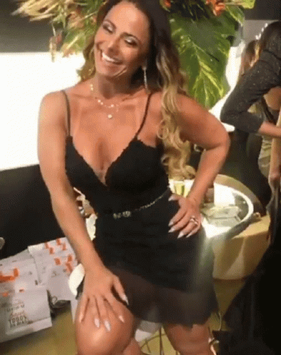 A Woman In A Black Dress Is Smiling With A License Plate That Says L9849 GIF