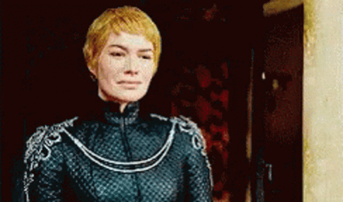 A Woman In A Black Dress Is Standing In Front Of A Door And Looking At The Camera . GIF