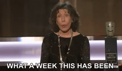 A Woman In A Black Dress Is Standing In Front Of A Microphone . GIF