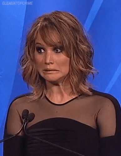 A Woman In A Black Dress Is Standing In Front Of A Microphone Making A Face . GIF