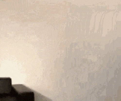 A Woman In A Black Dress Is Standing In Front Of A White Wall With A Sign That Says ' By Suzy ' On It GIF