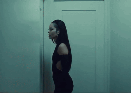 a woman in a black dress is standing next to a door in a dark room .