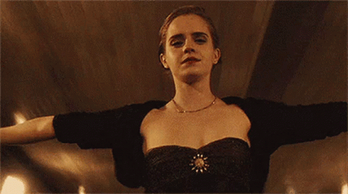A Woman In A Black Dress Is Standing With Her Arms Outstretched And Looking At The Camera . GIF