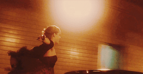 A Woman In A Black Dress Is Walking In Front Of A Building GIF
