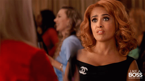 A Woman In A Black Dress With A Chanel Brooch GIF