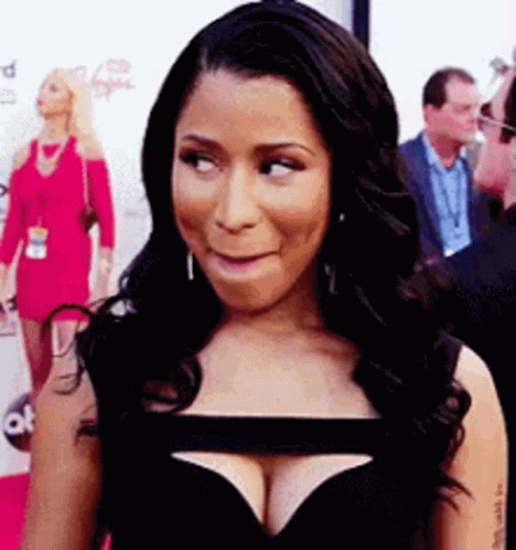 A Woman In A Black Dress With A Plunging Neckline Is Making A Funny Face . GIF