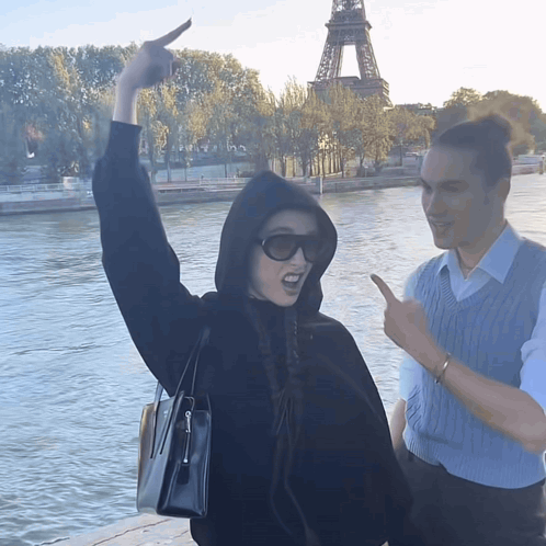 A Woman In A Black Hoodie Is Pointing At Something In The Distance GIF