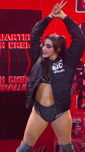 a woman in a black jacket and shorts is dancing in front of a sign that says quarterback crew .