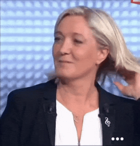 A Woman In A Black Jacket And White Shirt Is Holding Her Hair GIF