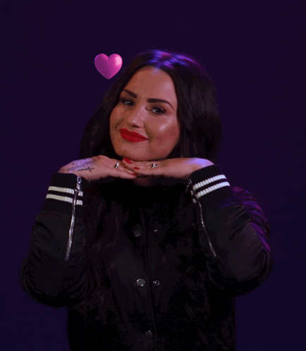 A Woman In A Black Jacket Has Hearts Floating Around Her Head GIF