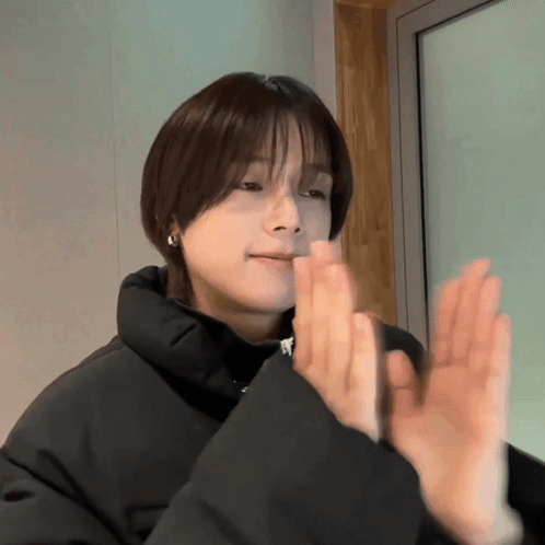 A Woman In A Black Jacket Is Clapping Her Hands Together GIF